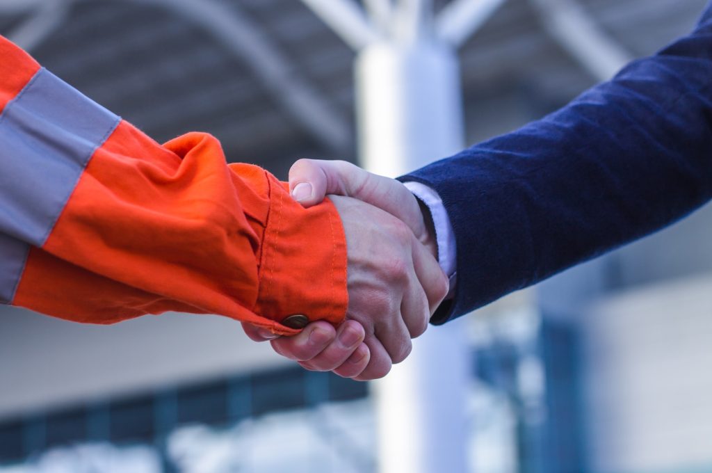 businessman handshaking with worker. Handshake of suit and boilersuit